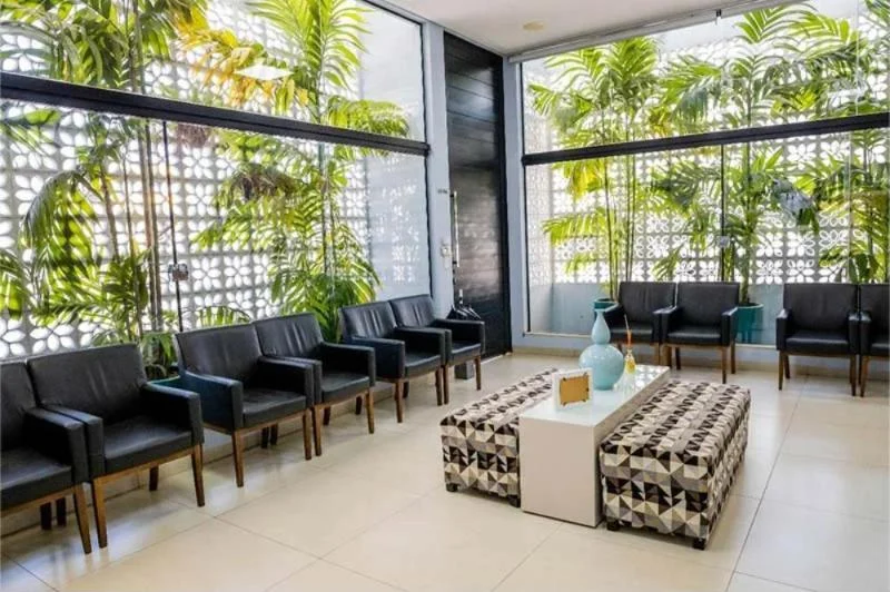 Sala de espera da Rahal Odontologia com parede de cobogó e palmeiras